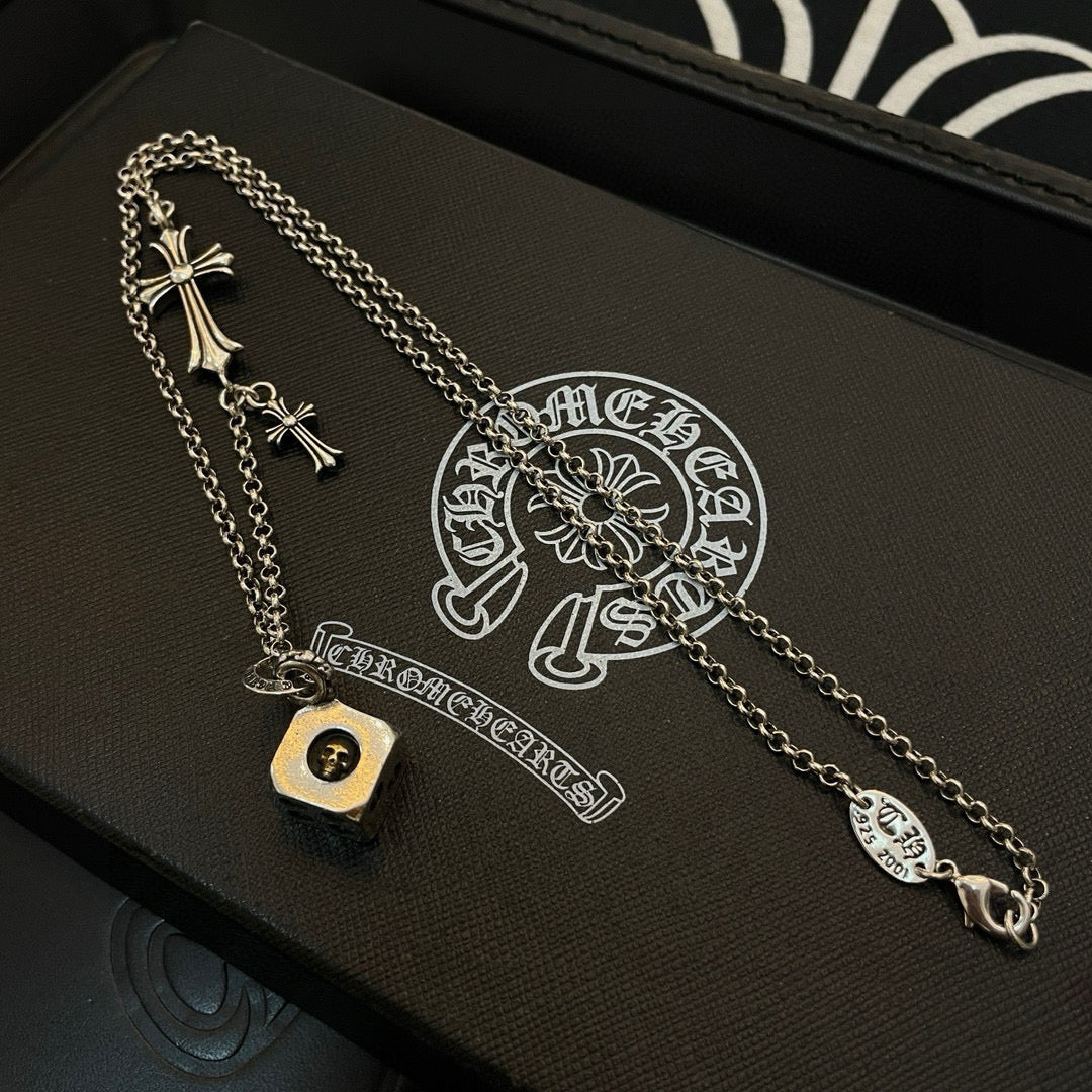 Silver cross charm necklace with round logo pendant on a black gift box