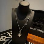 Silver cross charm necklace with round pendant on a mannequin display stand