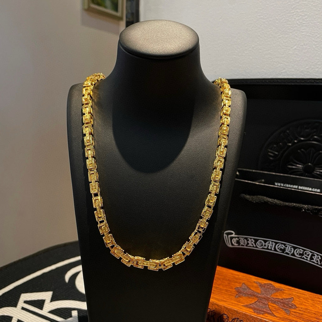 Gold tone chain necklace with chunky rectangular links on a black stand