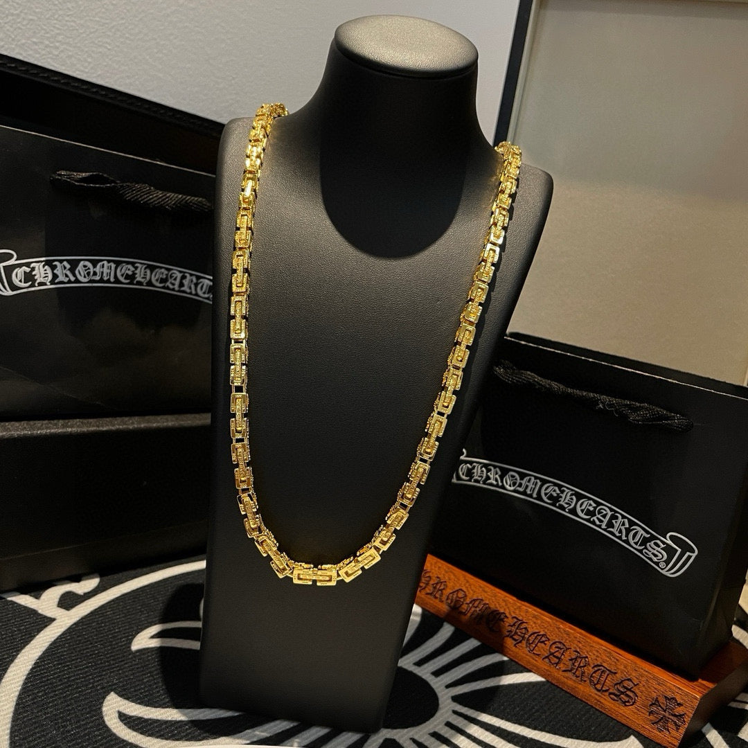 Gold tone chain necklace draped on a black jewelry stand, close front view