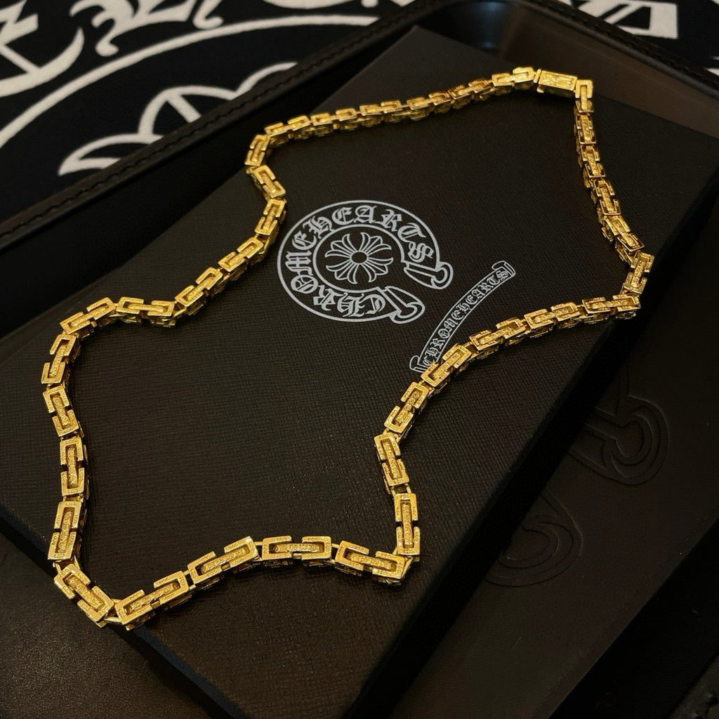 Gold tone chain necklace laid in a black box, curved rectangular link design