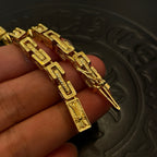 Gold tone chain bracelet and necklace links with engraved details, close-up