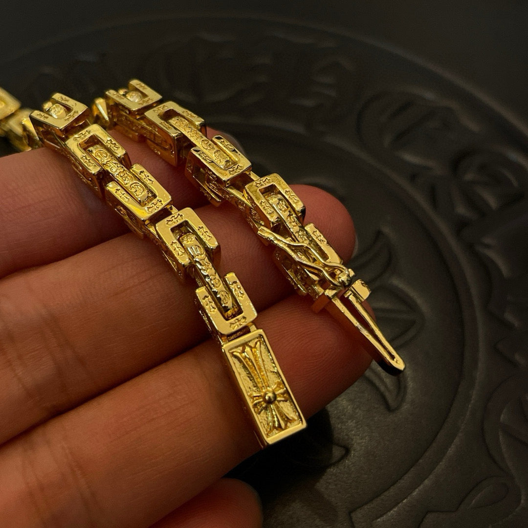 Gold tone chain bracelet and necklace links with engraved details, close-up