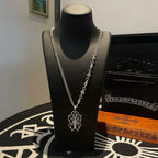 Silver-tone chain necklace with cross pendant on display bust