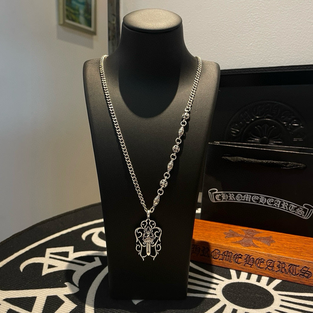 Silver-tone chain necklace with cross pendant on display bust