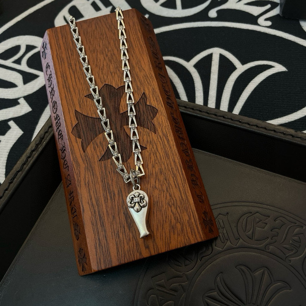 Silver-tone chain necklace with charm pendant, displayed on wooden box