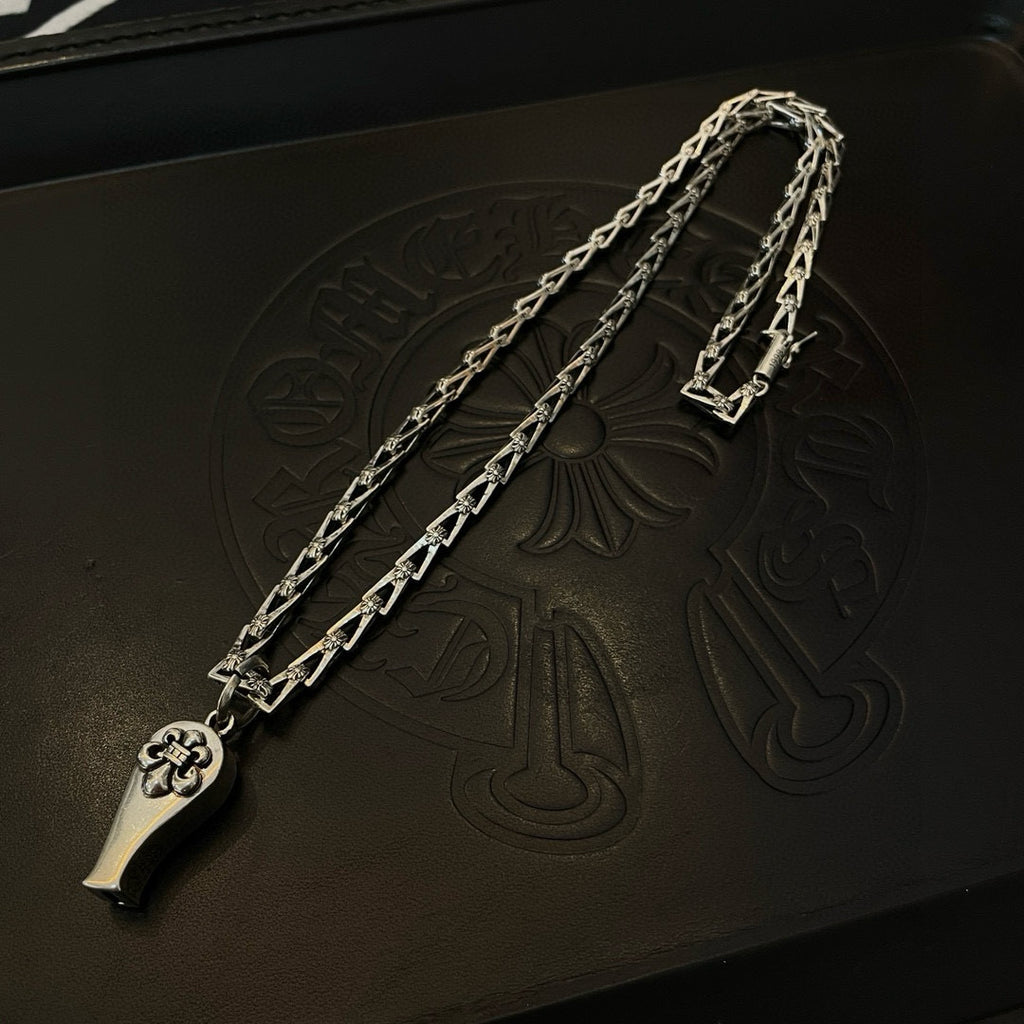 Silver-tone chain necklace with charm pendant, close-up on embossed black leather