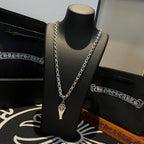 Silver-tone chain necklace with charm pendant, on black display bust