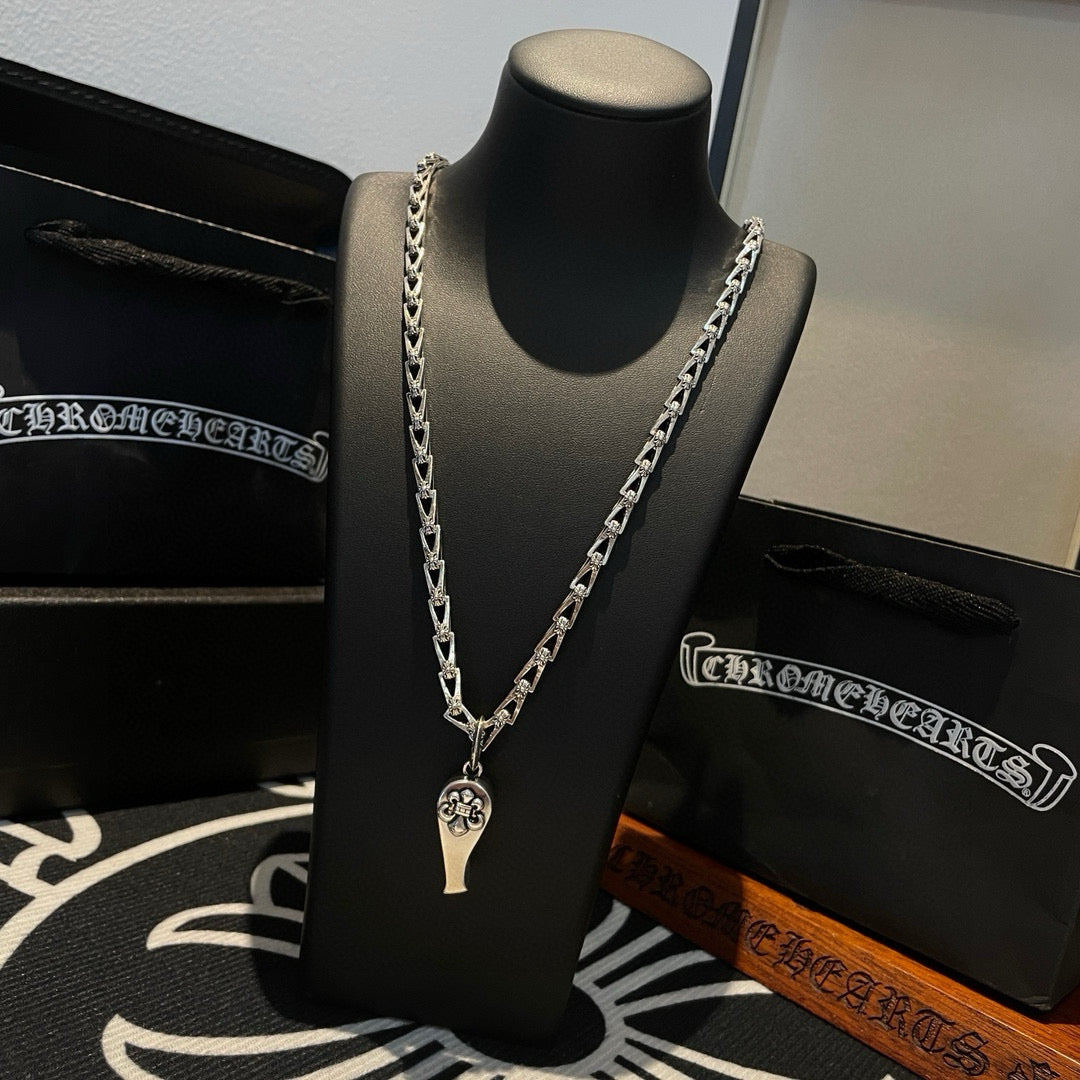 Silver-tone chain necklace with charm pendant, on black display bust