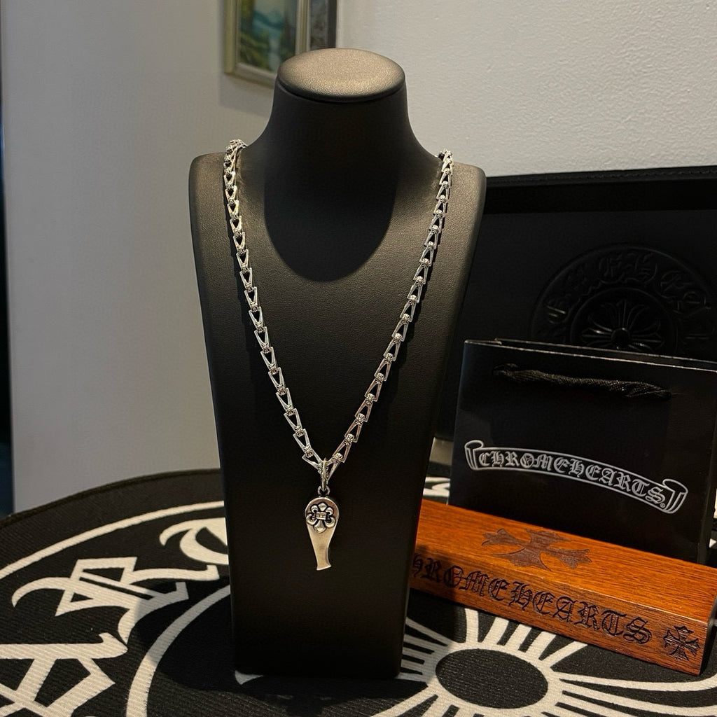 Silver-tone chain necklace with charm pendant, on black display bust