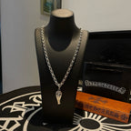 Silver-tone chain necklace with charm pendant, on black display bust