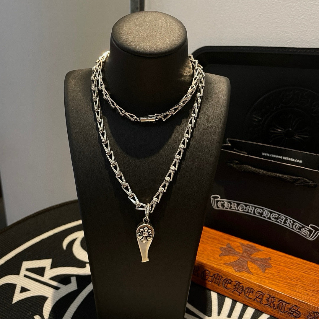 Silver-tone chain necklace with charm pendant, on black display bust