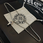 Silver-tone chain necklace with charm pendant, draped over fabric pouch