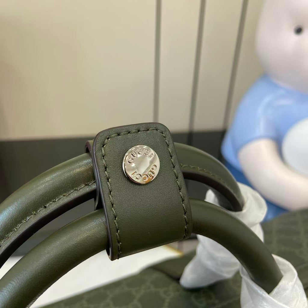 Gucci bag strap end with round silver logo snap hardware on dark green leather