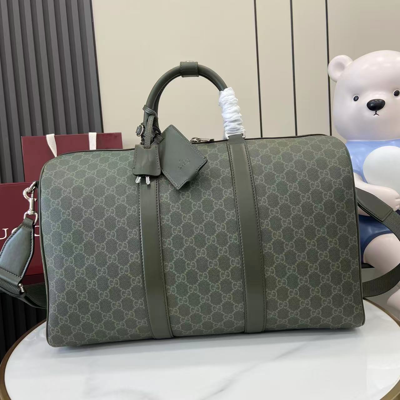 Gucci duffel bag in dark green GG canvas with top handles and front buckle detail