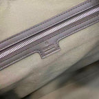 Gucci bag zipper close-up on beige fabric lining with logo tag and stitched trim