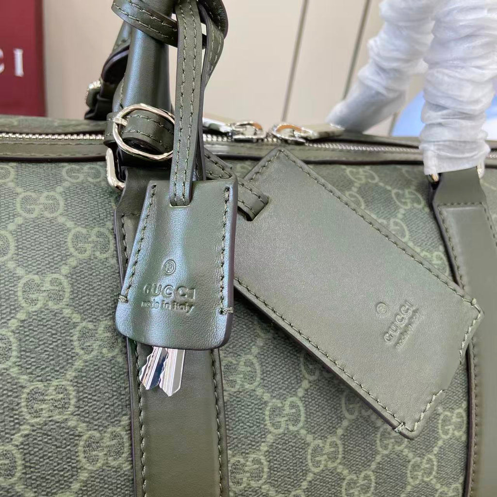 Gucci bag hardware close-up with dark green leather strap and Gucci logo charm