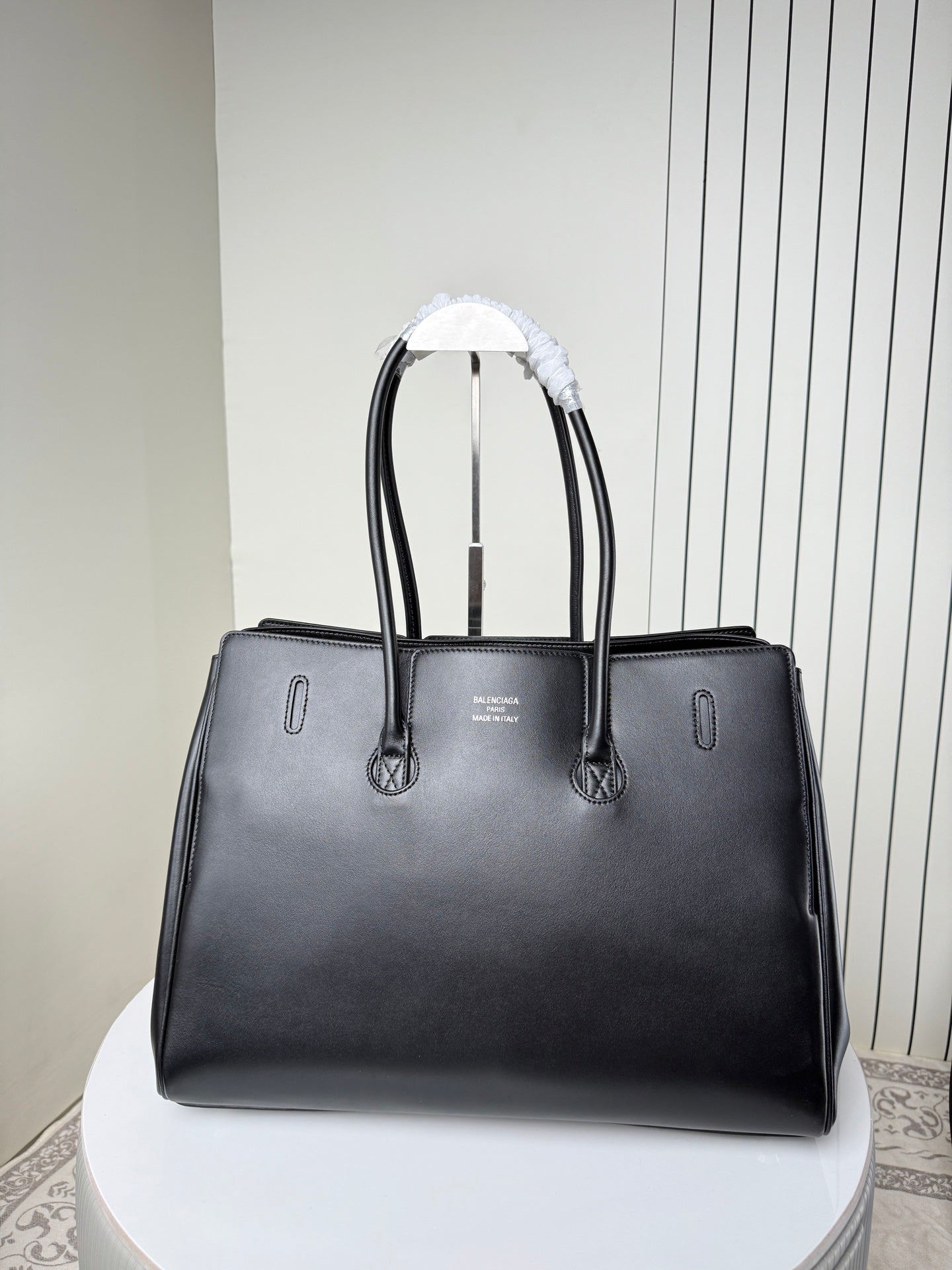Black leather tote bag front view with silver buckle and stitched details