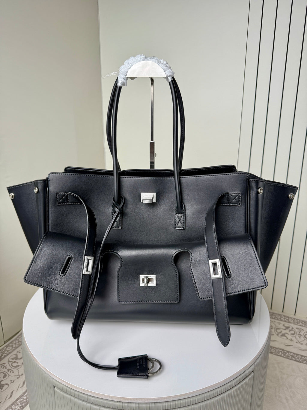 Black leather tote bag with top handles and front silver hardware