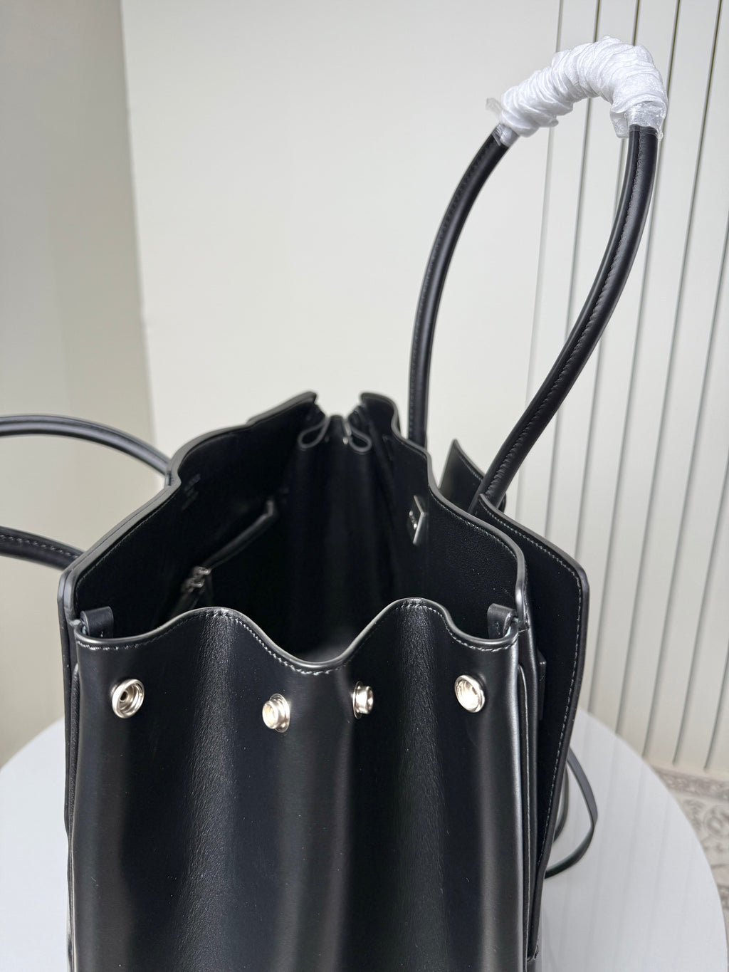 Black leather tote bag open view showing side pockets and silver studs