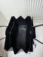 Black leather tote bag open top view with interior lining and label