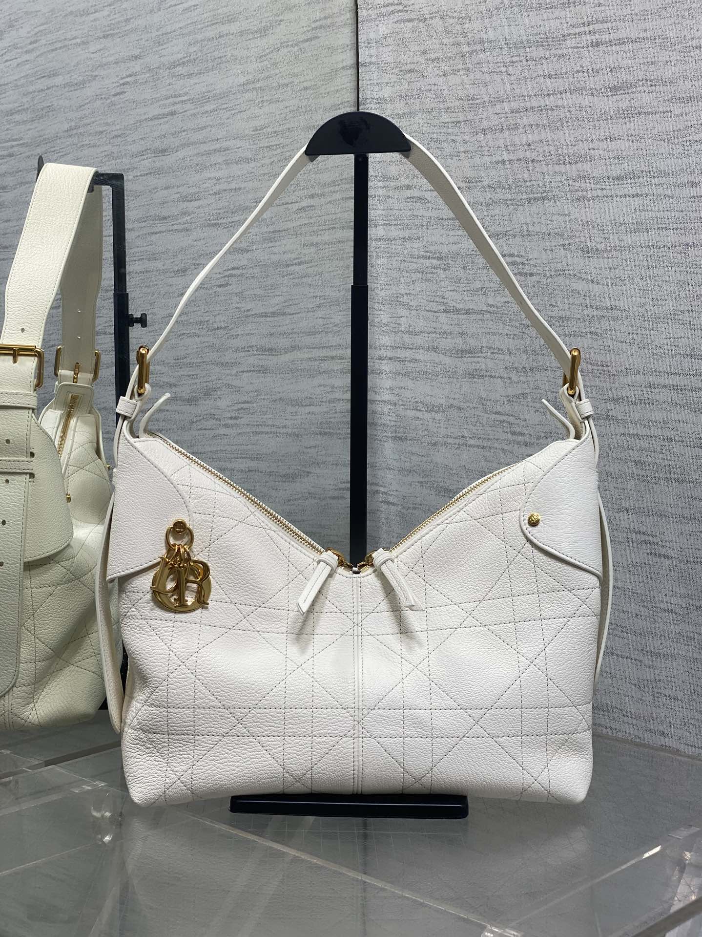 White quilted leather hobo bag with gold hardware, shoulder strap, and front snap detail