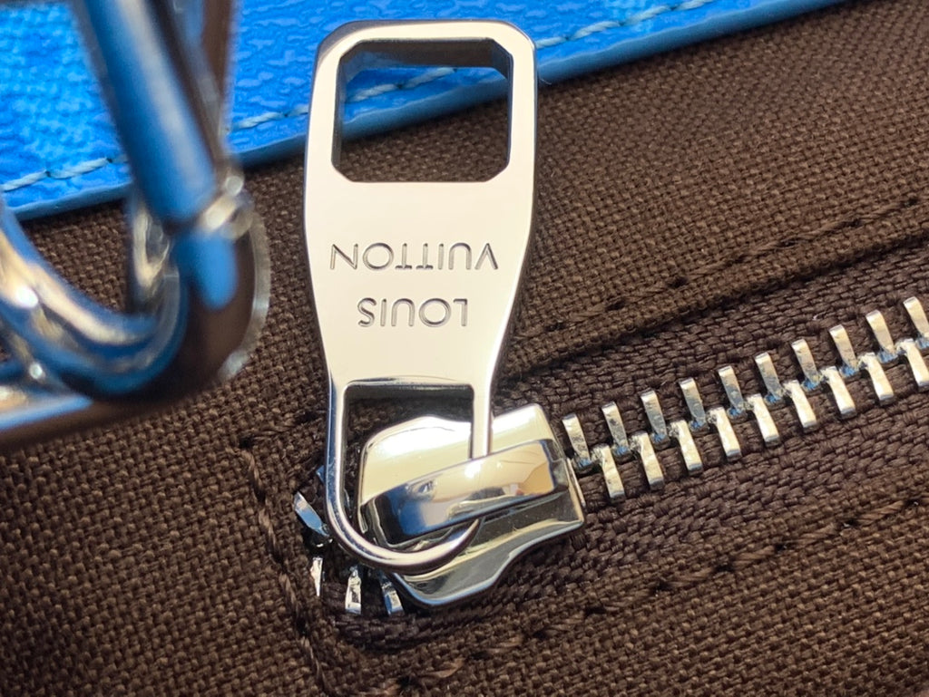 Engraved zipper pull on brown monogram handbag with blue leather trim