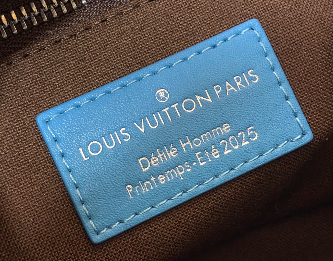 Blue leather logo tag on monogram handbag reading Louis Vuitton Paris Petite Homme