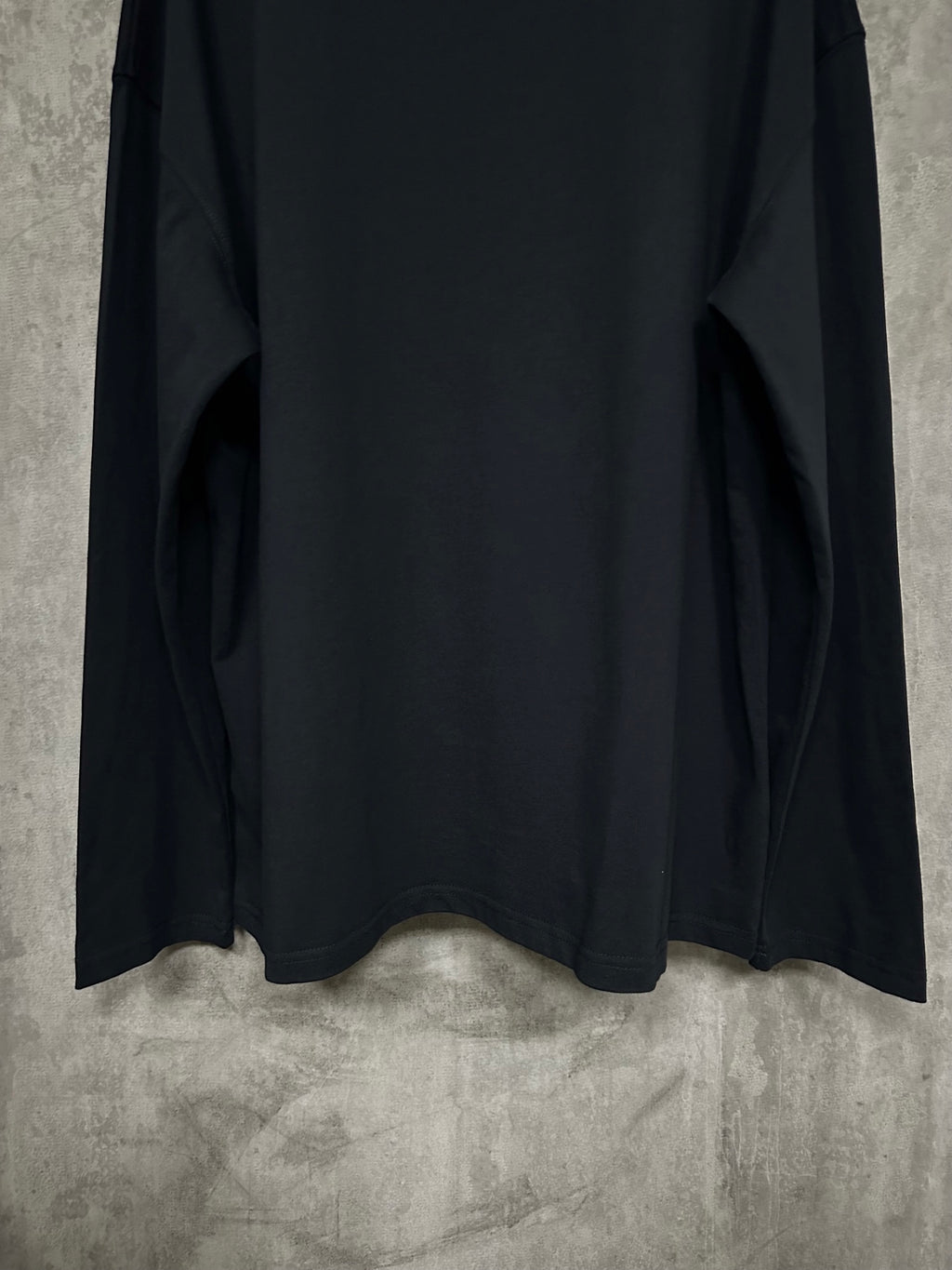 Black long-sleeve crewneck shirt, back view with lower hem