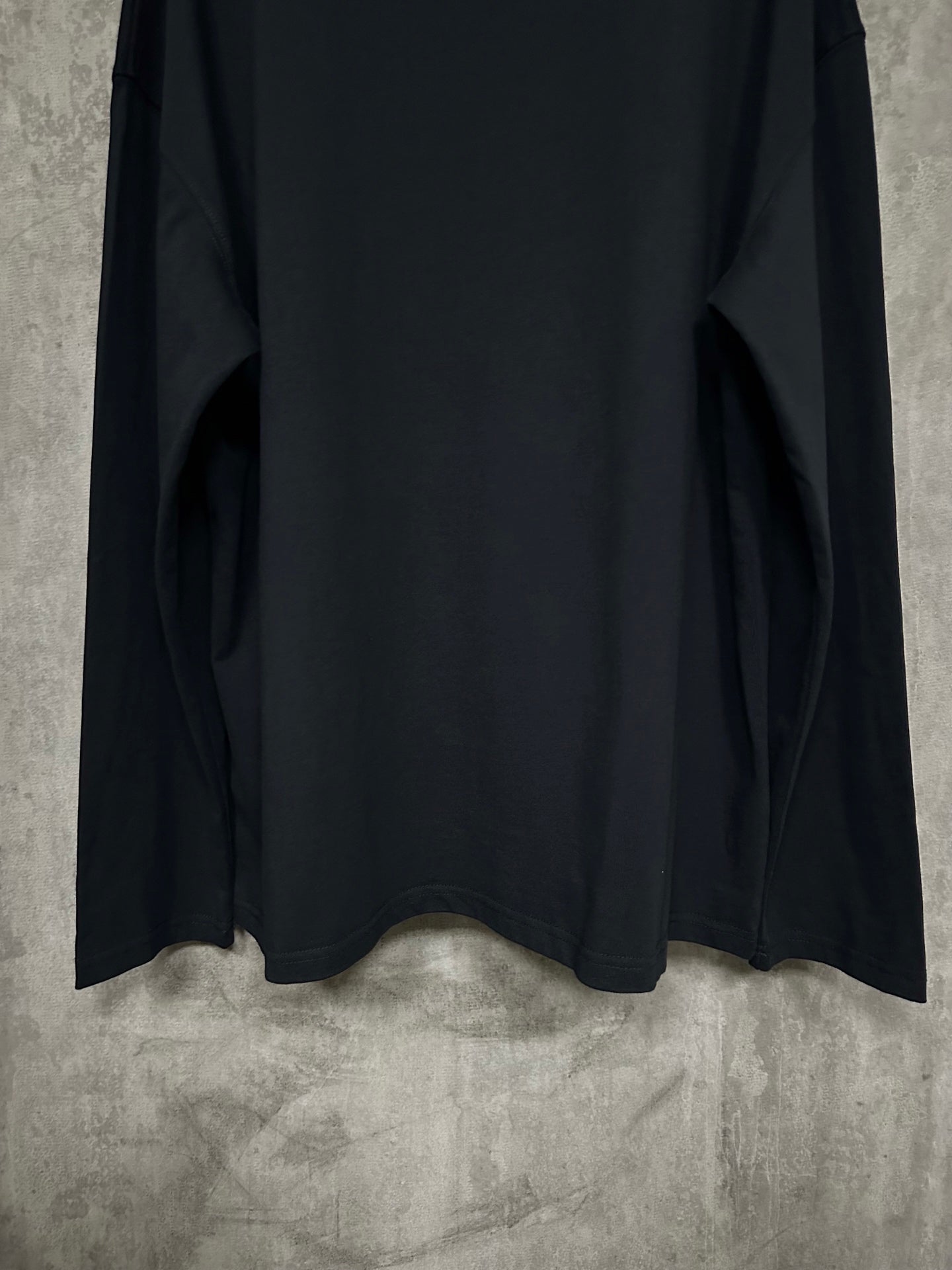 Black long-sleeve crewneck shirt, back view with lower hem