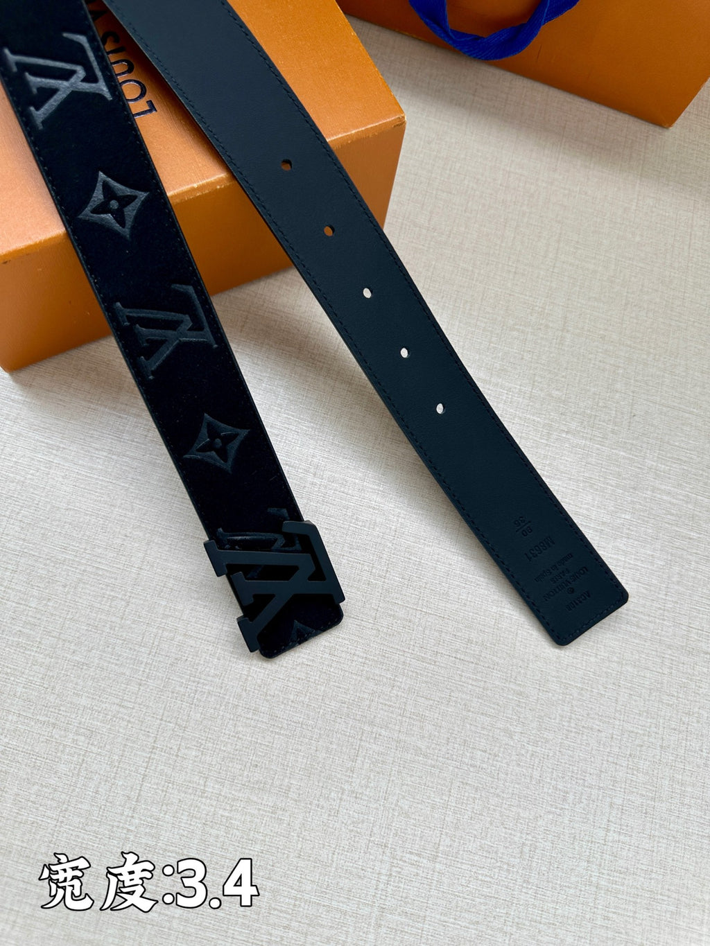 Leather belt straps close-up with dark monogram panel and perforated holes