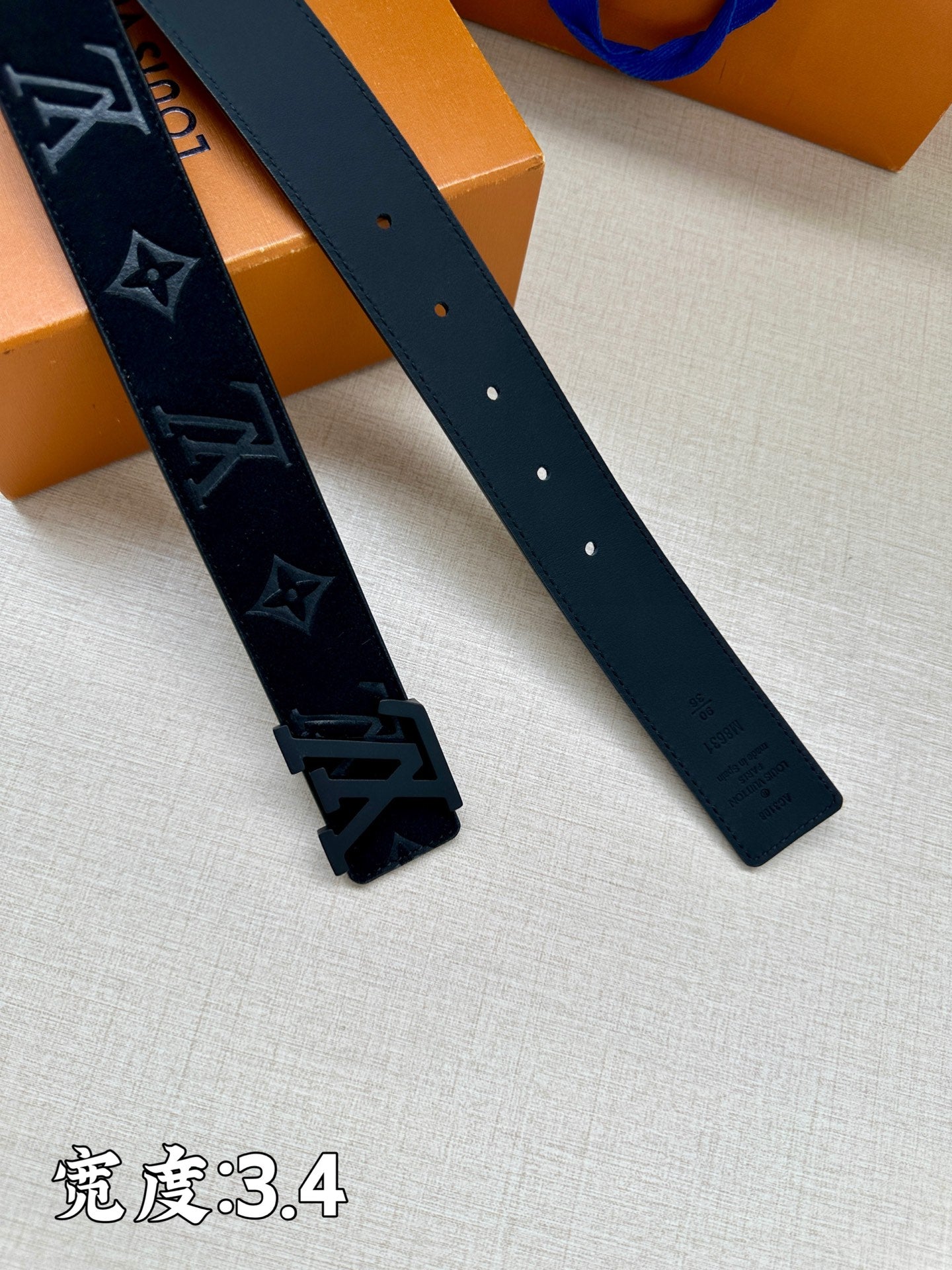 Leather belt straps close-up with dark monogram panel and perforated holes