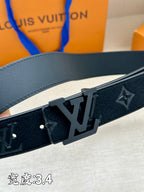 Leather belt close-up: dark monogram strap with metal buckle and studs