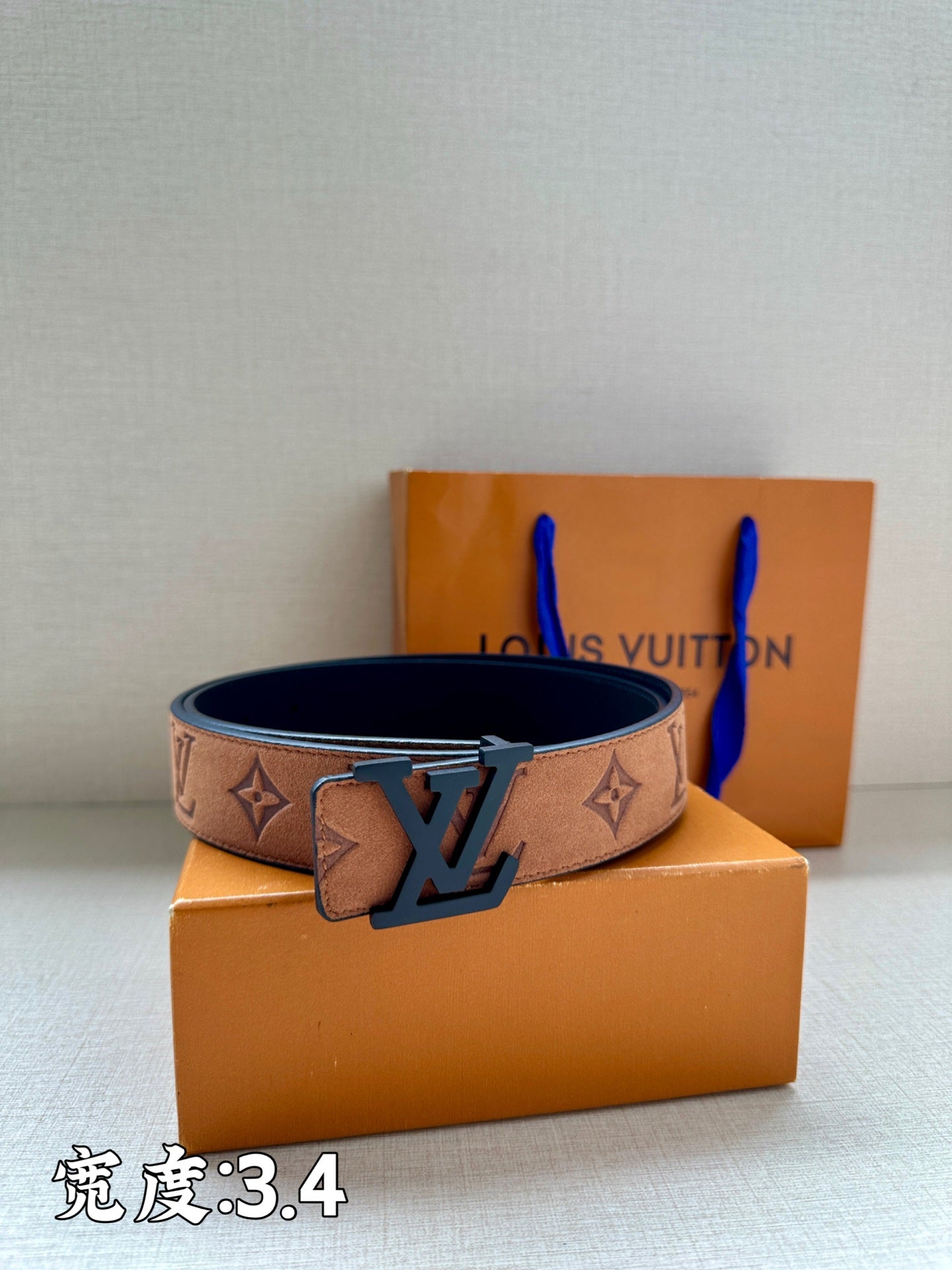Tan monogram belt with dark blue LV buckle, centered on boxes