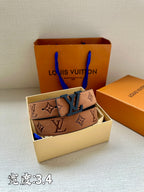 Tan monogram belt with dark blue LV buckle, laid on open gift box