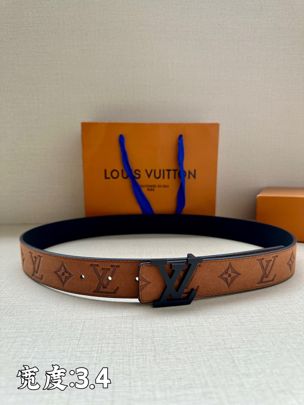 Monogram canvas belt with tan strap and dark blue LV buckle, with strap keeper