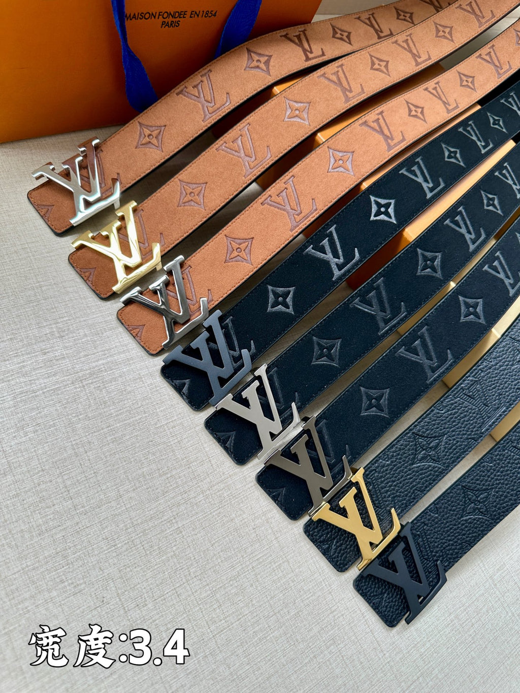 Monogram belts with tan and dark blue straps, each featuring an LV buckle