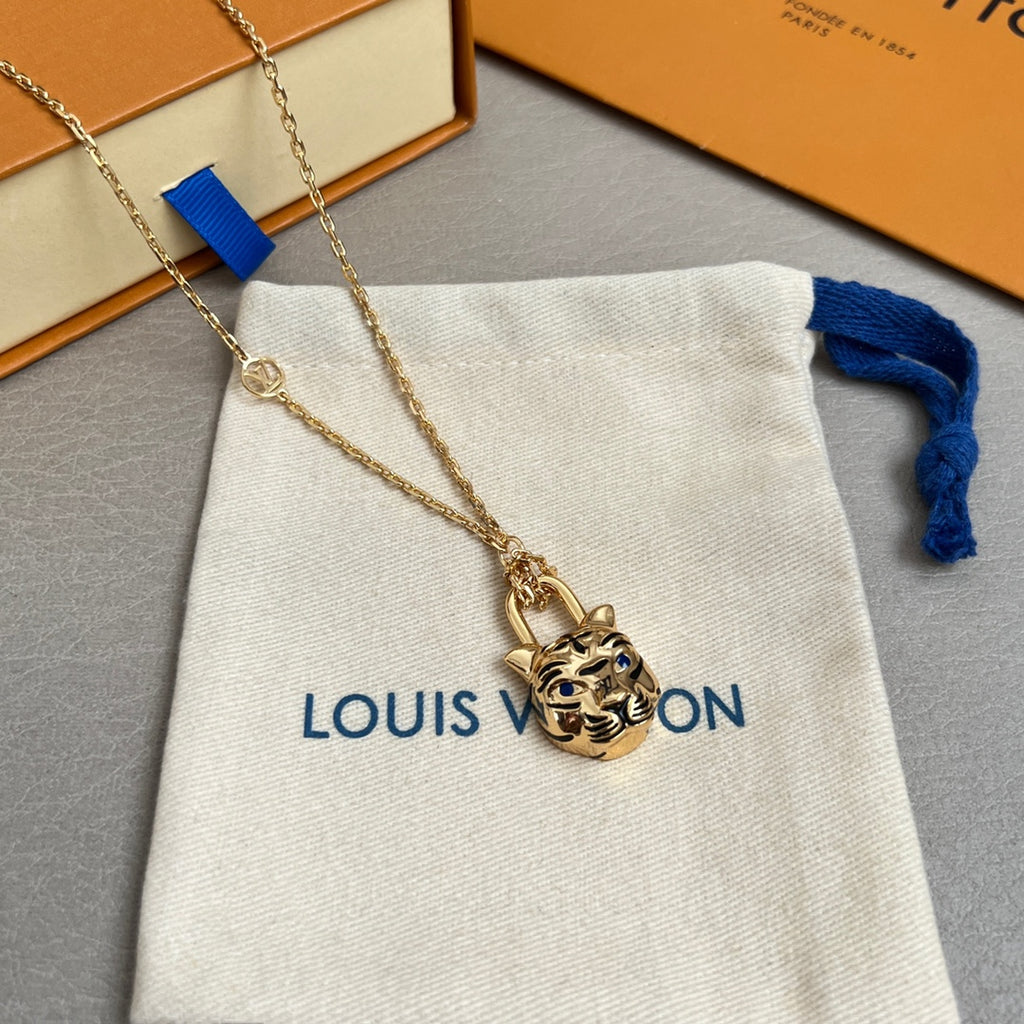 Gold-tone tiger-face pendant necklace close-up on white drawstring pouch with blue ribbon
