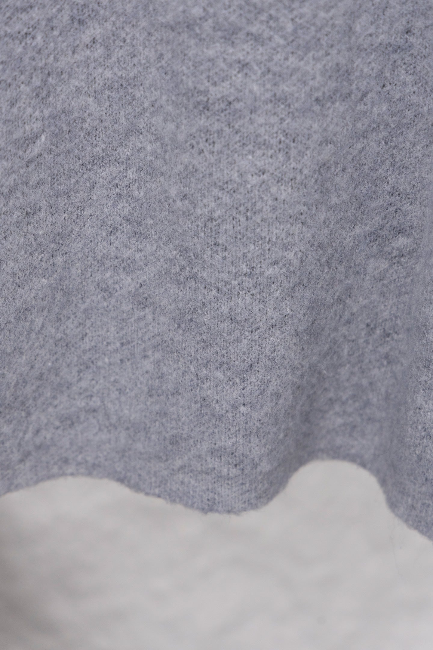 Gray knit sweater fabric texture with scalloped hem edge