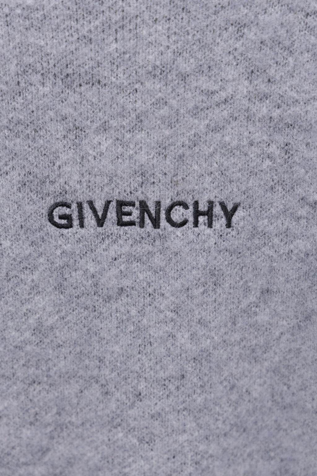 Gray knit sweater close-up with GIVENCHY lettering on front