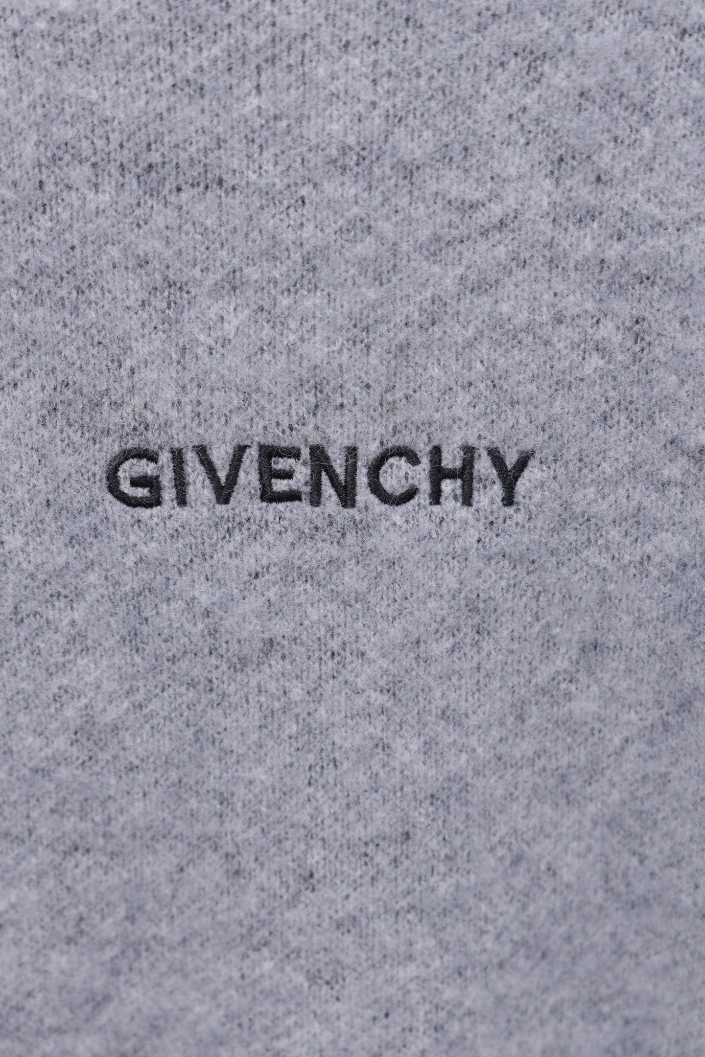 Gray knit sweater close-up with GIVENCHY lettering on front