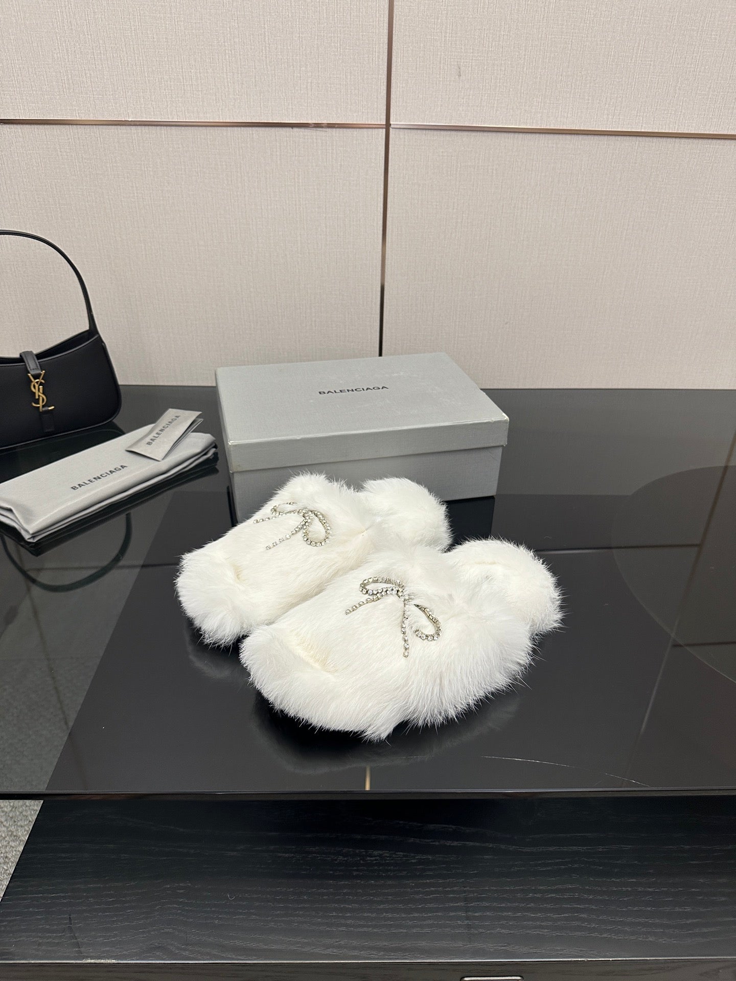 White faux fur slide sandals with silver bow-like logo charm detail