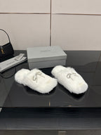 Pair of white faux fur slide sandals with silver logo charm on strap