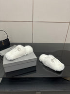White faux fur slide sandals on display with silver logo charm on top