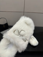 Close-up of white faux fur slide sandal with silver logo charm detail