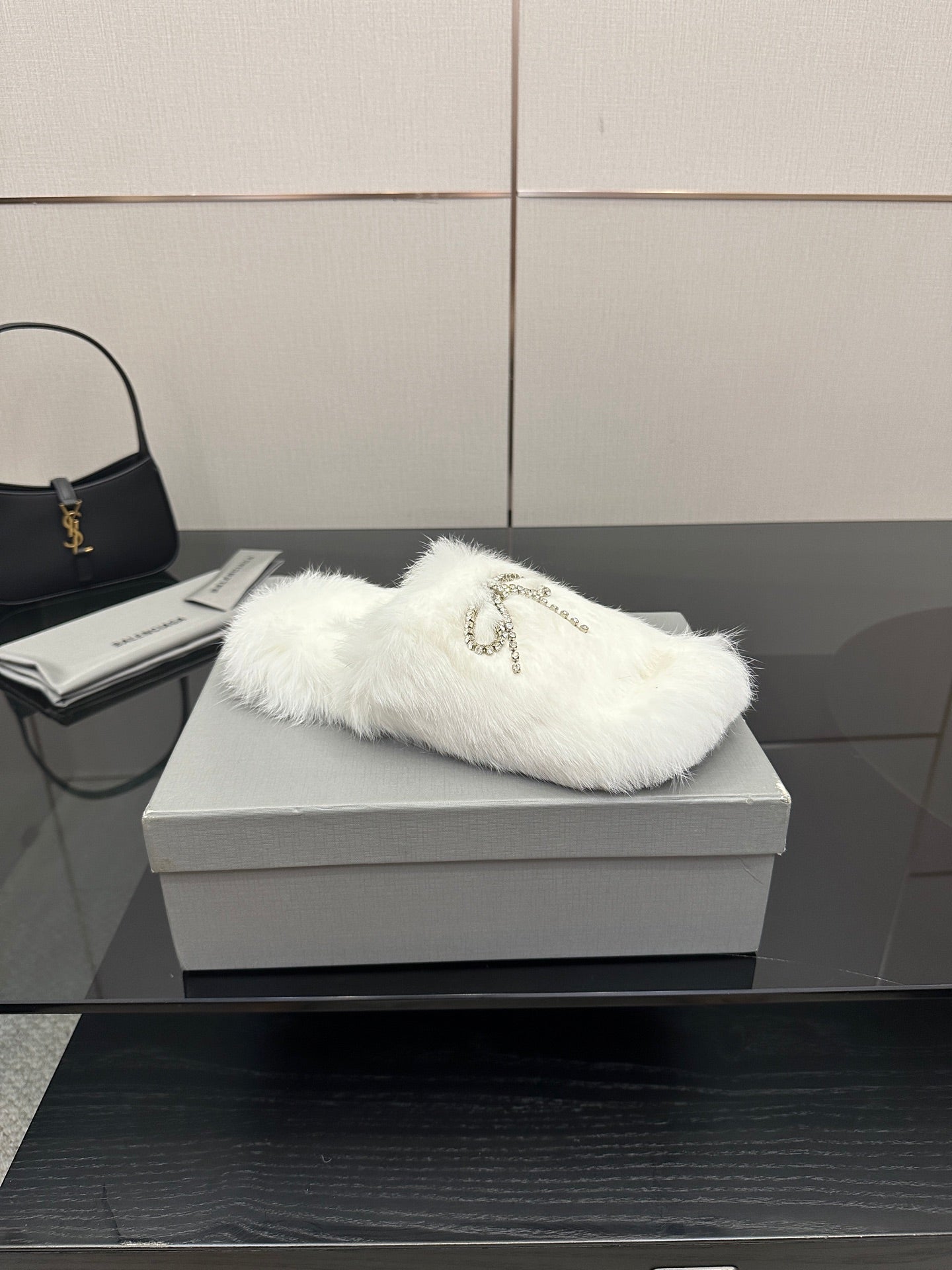 White faux fur slide sandals with silver logo charm on strap