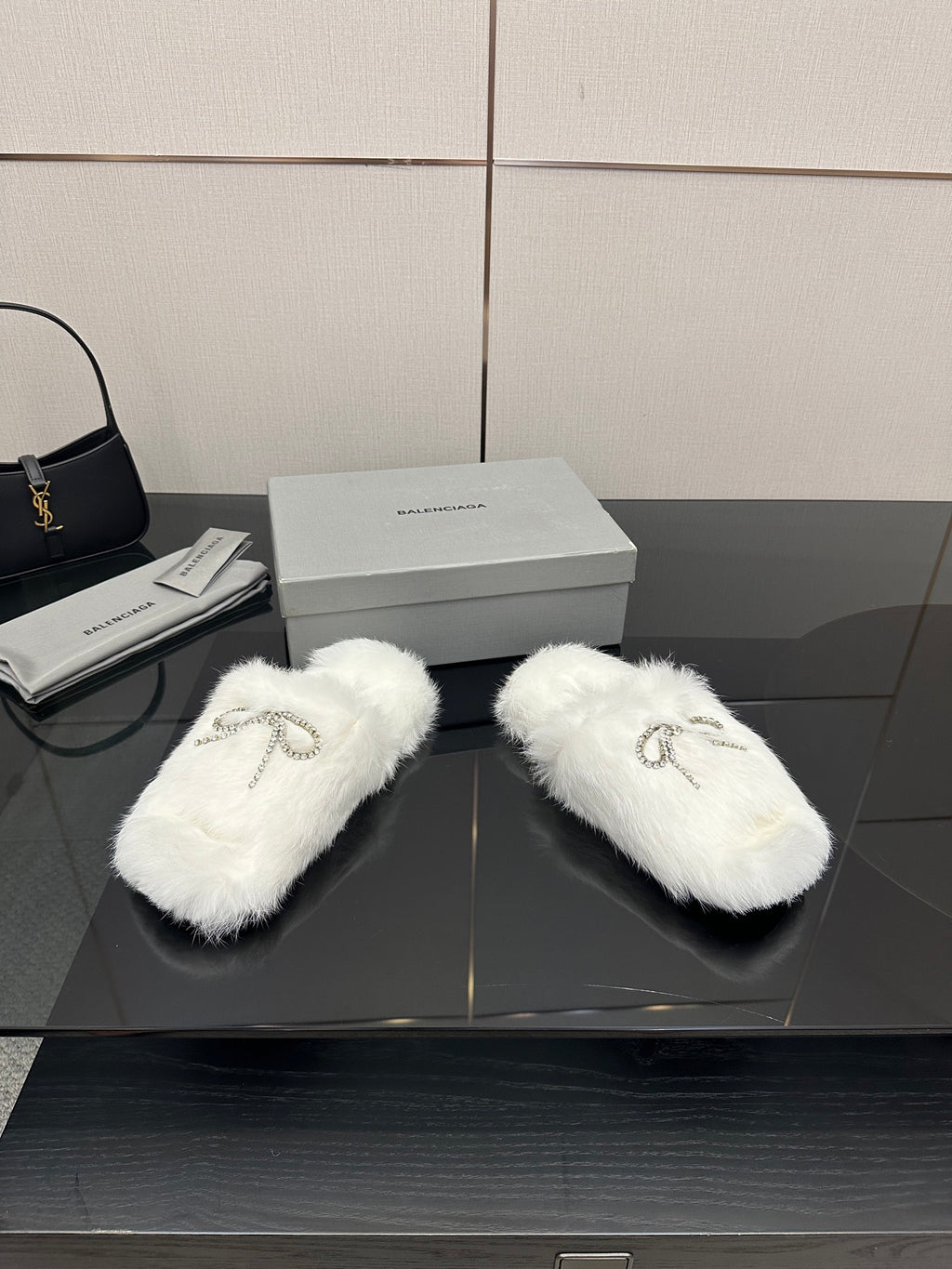 White faux fur slide sandals with silver logo charm on top