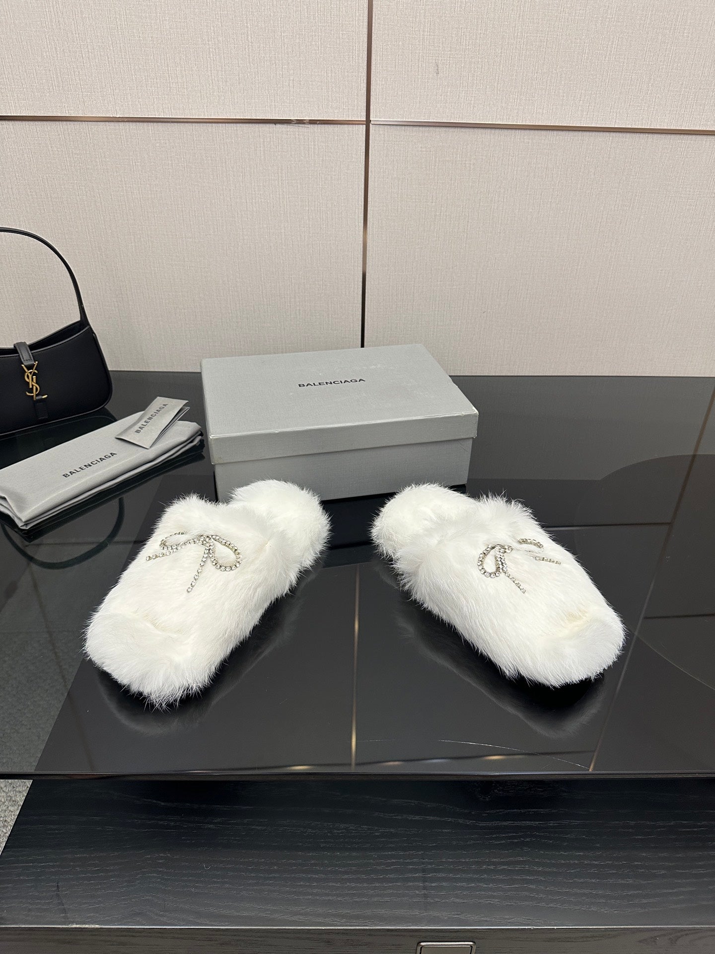 White faux fur slide sandals with silver logo charm on top