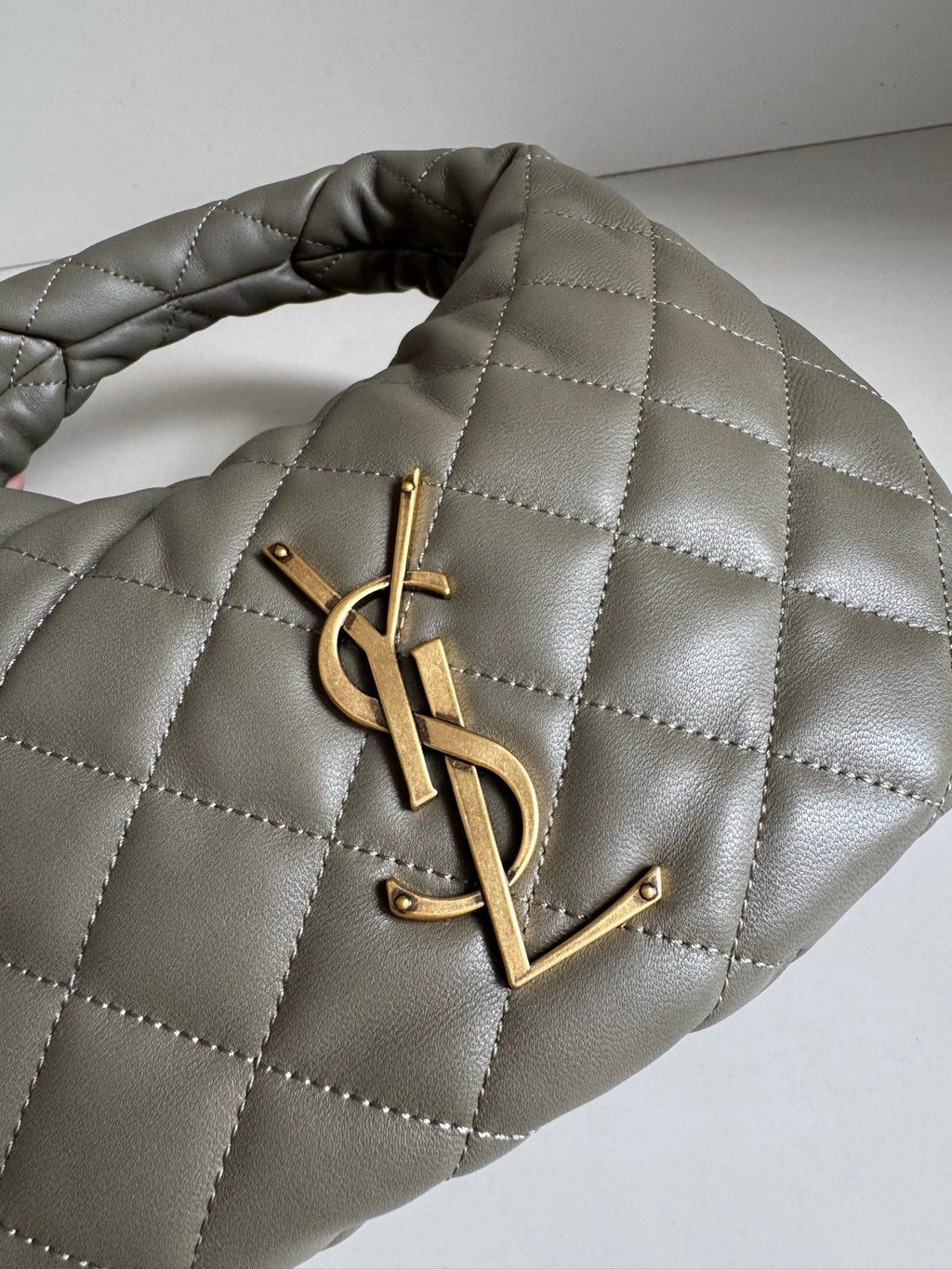 Quilted hobo bag in metallic gray with gold YSL logo at center front