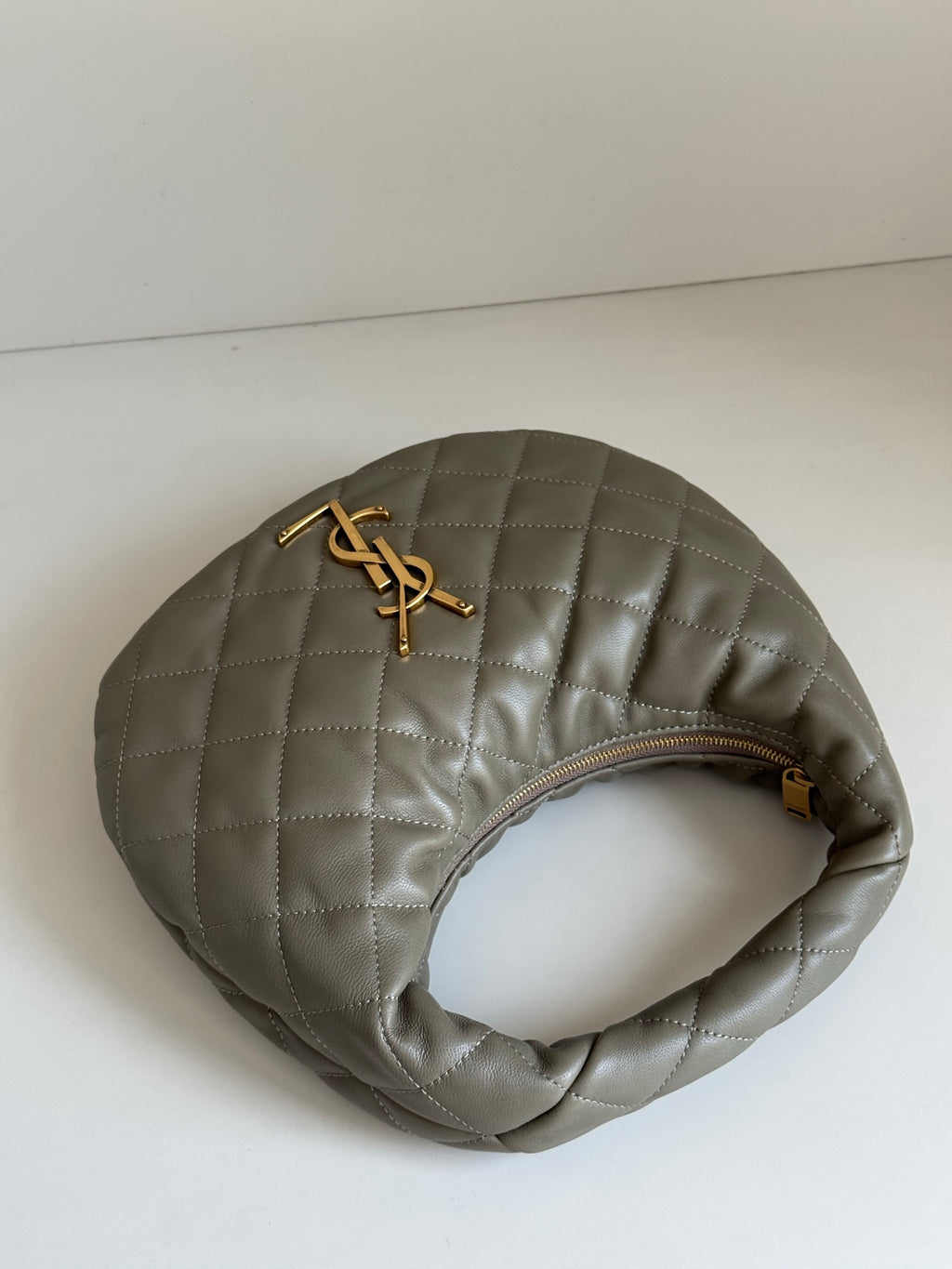 Quilted hobo bag in metallic gray with gold YSL logo and rounded top opening